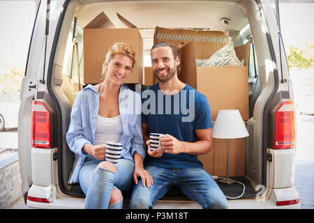 Couple Taking A Break In Back Of Removal Truck On Moving Day Stock Photo