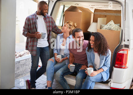 Friends Helping Couple To Unload Removal Truck On Moving Day Stock Photo