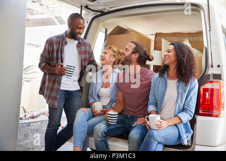 Friends Helping Couple To Unload Removal Truck On Moving Day Stock Photo