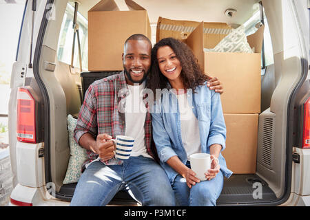 Couple Taking A Break In Back Of Removal Truck On Moving Day Stock Photo