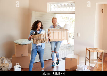 Female Friends Carrying Boxes Into New Home On Moving Day Stock Photo