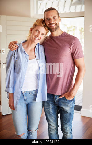 Portrait Of Couple By Open Front Door In Lounge Of New Home Stock Photo