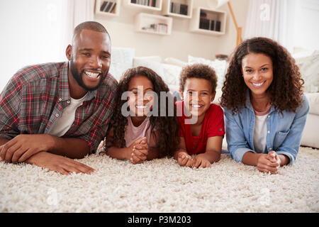 Portrait Of Family Lying On Rug In Lounge At Home Stock Photo