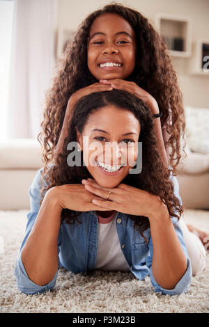 Portrait Of Daughter Lying On Mothers Back In Lounge Stock Photo