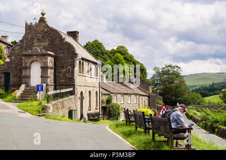 Walker resting on a bench by Muker Literary Institute in Yorkshire Dales National Park village of Muker Swaledale North Yorkshire England UK Britain Stock Photo