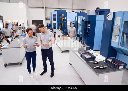 Engineers Meeting On Factory Floor Of Busy Engineering Workshop Stock Photo