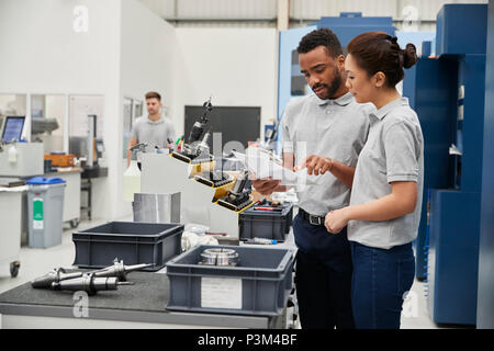 Engineer And Apprentice Meet On Floor Of Engineering Workshop Stock Photo