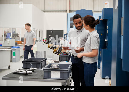 Engineer And Apprentice Meet On Floor Of Engineering Workshop Stock Photo
