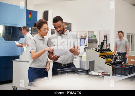 Engineer And Apprentice Meet On Floor Of Engineering Workshop Stock Photo