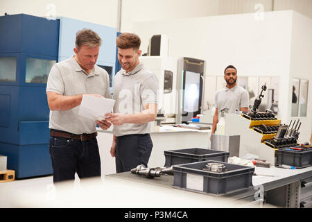 Engineer And Apprentice Meet On Floor Of Engineering Workshop Stock Photo