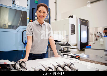 Portrait Of Female Engineer With CAD Drawings In Factory Stock Photo