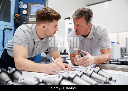 Engineer Showing Apprentice How To Measure CAD Drawings Stock Photo