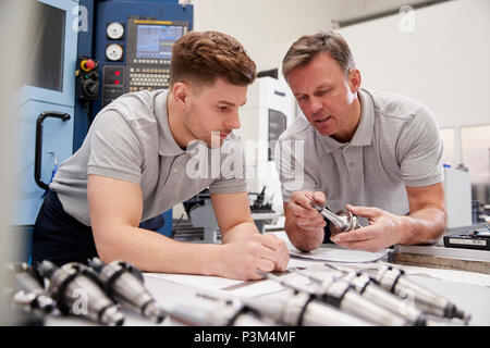 Engineer Showing Apprentice How To Measure CAD Drawings Stock Photo