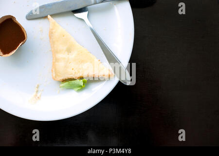 Dirty plate with the remains of a sandwich and sauce. Black table. Lunch at the cafe. Fork and knife. Place for text. Stock Photo