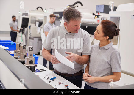 Engineer And Female Apprentice Discussing Job Sheet In Factory Stock Photo