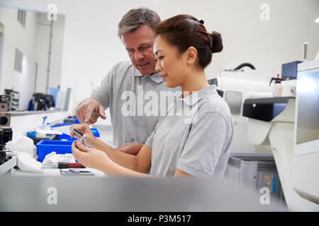 Engineer And Female Apprentice Measuring Components In Factory Stock Photo