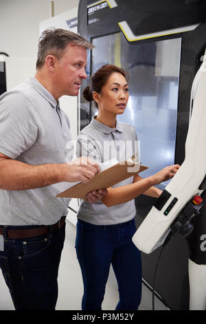 Engineer Training Female Apprentice To Use CNC Machine In Factory Stock Photo