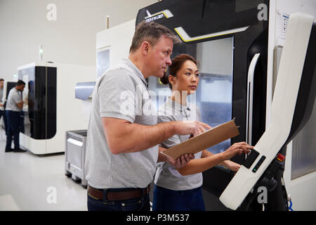 Engineer Training Female Apprentice To Use CNC Machine In Factory Stock Photo