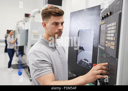 Male Engineer Operating CNC Machinery In Factory Stock Photo