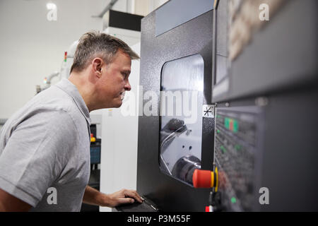 Male Engineer Watching Progress Of CNC Machinery In Factory Stock Photo