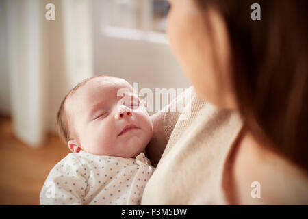 Close Up Of Sleeping Newborn Baby Being Held By Mother Stock Photo