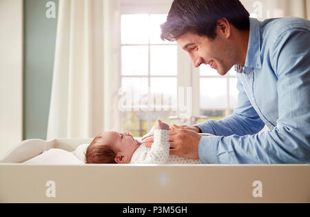 Father Playing With Newborn Baby Lying On Changing Table Stock Photo