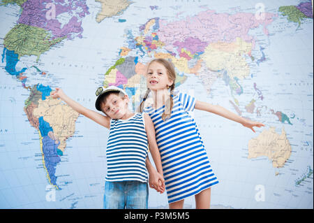 two happy cute kids in striped sailor shirts on world map background Stock Photo