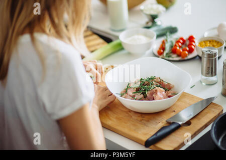 Home cozy kitchen chef pours salt on pork or beef meat with salt shaker Barbecue concept or healthy meat lifestyle shot Stock Photo