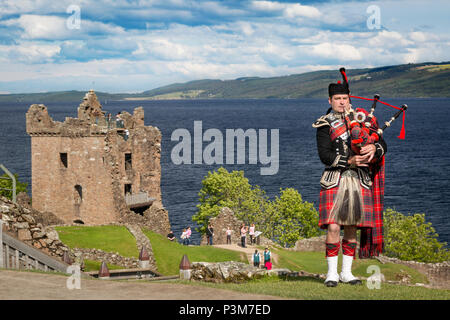 Bagpiper playing near the ruins of Urquhart Castle along the shores of Loch Ness, Highlands, Scotland, UK Stock Photo