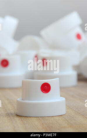 Several new plastic nozzles from a paint sprayer that lie on a wooden surface against a gray wall background. The concept of street art and graffiti Stock Photo