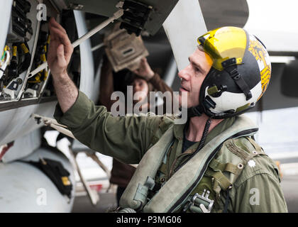 160713-N-NF288-093 SOUTH CHINA SEA (July 13, 2016) Cmdr. Adrian Calder, commanding officer of the “Royal Maces” of Strike Fighter Squadron (VFA) 27, performs a pre-flight inspection on his F/A-18E Super Hornet on the flight deck of the Navy’s only forward-deployed aircraft carrier, USS Ronald Reagan (CVN 76). Cmdr. Daniel Cochran relieved Calder as the new commanding officer of VFA-27 during a change of command ceremony held partly in the skies above the carrier. Ronald Reagan, the Carrier Strike Group Five (CSG 5) flagship, is on patrol in the U.S. 7th Fleet area of responsibility supporting  Stock Photo