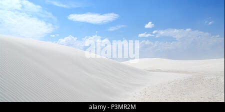 White sand dunes with wind formed ripples on a day with blue skies and clouds Stock Photo