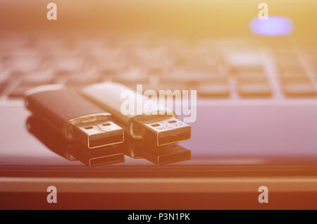 USB flash cards lying on black laptop case in front of his keyboard. Virtual memory storage with USB output Stock Photo