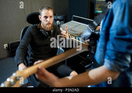 Sound producer talking to musician in studio Stock Photo