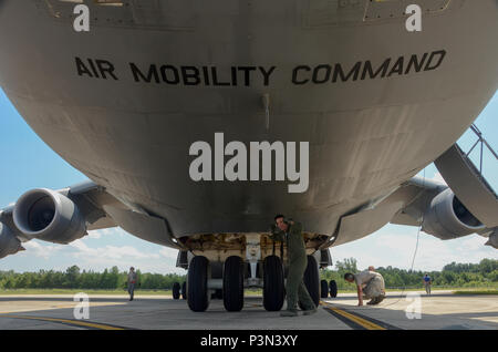 U.S. Air Force Tech. Sgt. Jake Schlemmer, a flight engineer assigned to the 709th Airlift Squadron, poses under a U.S. Air Force Lockheed C-5 Galaxy transport aircraft at McEntire Joint National Guard Base, S.C., July 8, 2016. Approximately 300 U.S. Airmen and 12 F-16 Fighting Falcon jets from the 169th Fighter Wing at McEntire JNGB, S.C., are deploying to Osan Air Base, Republic of Korea, as the 157th Expeditionary Fighter Squadron in support of the U.S. Pacific Command Theater Security Package. (U.S. Air National Guard photo by Airman 1st Class Megan Floyd) Stock Photo