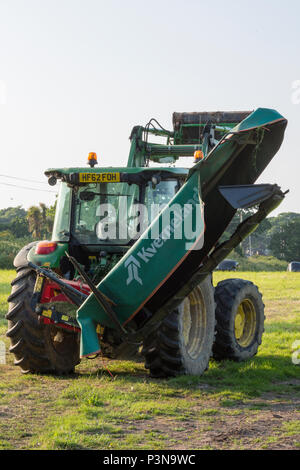 a large agricultural farm tractor with a mower attached to the rear on it's power take off or PTO shaft. agricultural implements and farming fields. Stock Photo