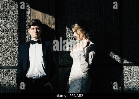 A young, sympathetic couple strolling around the city and posing against the background of the pink wall Stock Photo