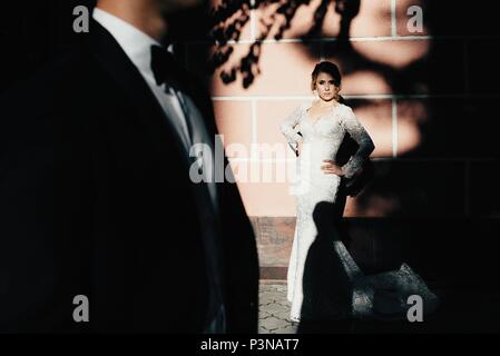 A young, sympathetic couple strolling around the city and posing against the background of the pink wall Stock Photo