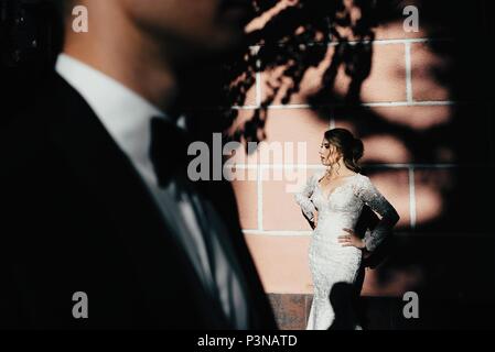 A young, sympathetic couple strolling around the city and posing against the background of the pink wall Stock Photo