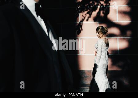 A young, sympathetic couple strolling around the city and posing against the background of the pink wall Stock Photo