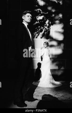 A young, sympathetic couple strolling around the city and posing against the background of the pink wall Stock Photo