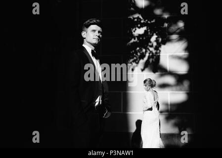 A young, sympathetic couple strolling around the city and posing against the background of the pink wall Stock Photo