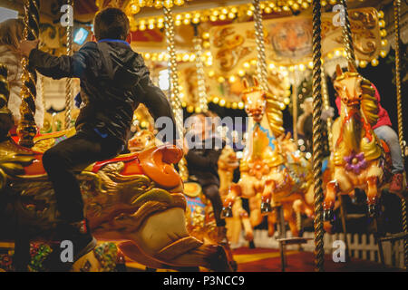 London, UK - December 2017. Kids riding horses on the carousel at the National History Museum in South Kensington. Landscape format. Stock Photo