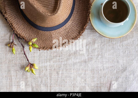 Top view of Summer brown panama straw hat with cup of tea and flower plant on linen cloth.travel concept.copy space for adding text Stock Photo