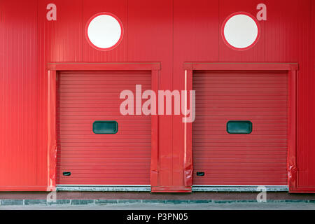 loading docks with closed shutter doors on red wall of distribution warehouse Stock Photo