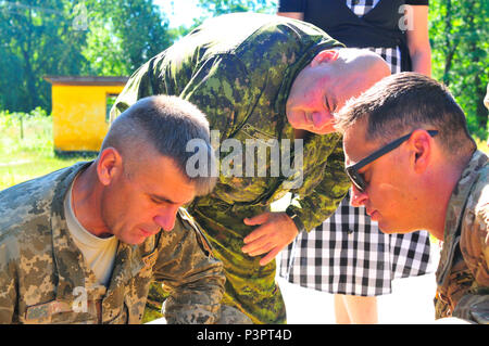 YAVORIV, Ukraine--Ukrain Army Col. Vikter Sphin, deputy commander of the International Peacekeeping and Security Center (left) speaks with U.S. Army Capt. Jason Ayres (right) and Canadian Army Master Warrant Officer Luc Desrochers (center) about the new Range Operations building here. Joint Multinational Training Group-Ukraine is focused on the development of the IPSC into a fully-functional combat training center by implementing, developing or improving upon capabilities such as infrastructure, equipment, cadre, doctrine and standard operating procedures. (Army photo by Capt. Scott Kuhn) Stock Photo