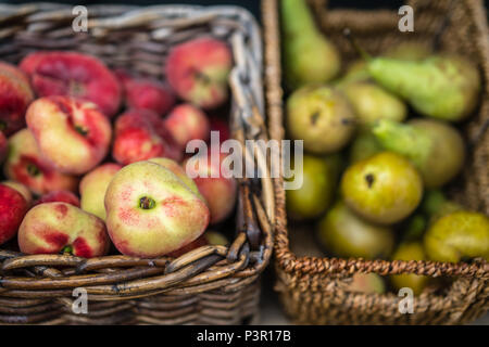 Nectarines and pears in wicker basket on display on a stall at farmers market in Cornwall, Uk Stock Photo