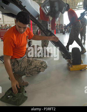 Airman 1st Class from the Tiger Aircraft Maintenance Unit performs maintenance on an MQ-9 Reaper during the Load Crew of the Quarter competition July 1, 2016, at Creech Air Force Base, Nevada. Two three-man crews are responsible for loading munitions safely under a time limit. The exercise ensures operational readiness, safety compliance, proficiency, and teamwork in handling unmanned aircraft systems. Stock Photo