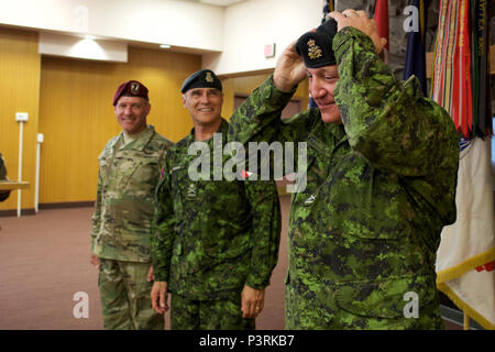 Canadian Army Brig. Gen. Martin Frank (right), U.S. Army Alaska deputy commander - operations, receives a beret with his new rank insignia from Canadian Army Maj. Gen. J.C.G. Juneau, Canadian Army deputy commander, as U.S. Army Maj. Gen. Bryan Owens, USARAK commander, looks on during the newly minted brigadier general's July 22 promotion at Joint Base Elmendorf-Richardson. Martin will soon take an assignment in Canada. (U.S. Air Force photo by David Bedard) Stock Photo