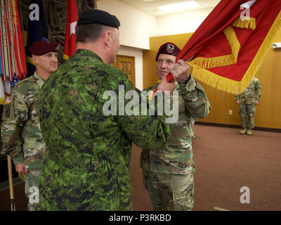 U.S. Army Maj. Gen. Bryan Owens (right), U.S. Army Alaska commander, hands a U.S. Army brigadier general flag to Canadian Army Brig. Gen. Martin Frank, USARAK deputy commander - operations, during the newly minted brigadier general's July 22 promotion at Joint Base Elmendorf-Richardson. Generals and admirals are often called flag officers because of the banner that accompanies them. (U.S. Air Force photo by David Bedard) Stock Photo